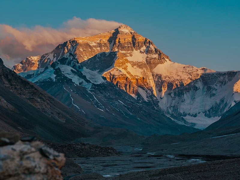 Golden sunset light illuminating the snow-capped peak of Mount Everest as seen from Base Camp.