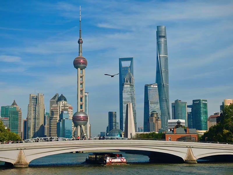 Historic Waibaidu Bridge (Garden Bridge) over Suzhou Creek with Lujiazui skyline in background.