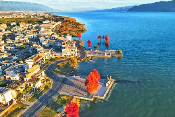 Aerial view of Erhai Lake in Dali, featuring blue water, lakeside town, autumn trees, and surrounding mountains