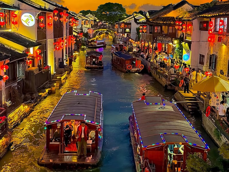 Night view of Shantang Street canal with illuminated tour boats and red lanterns.